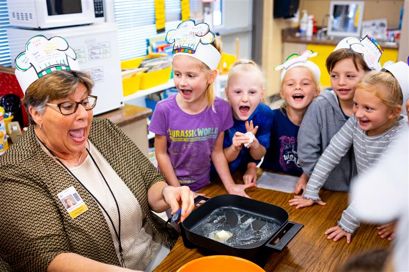 A teacher and students crack an egg